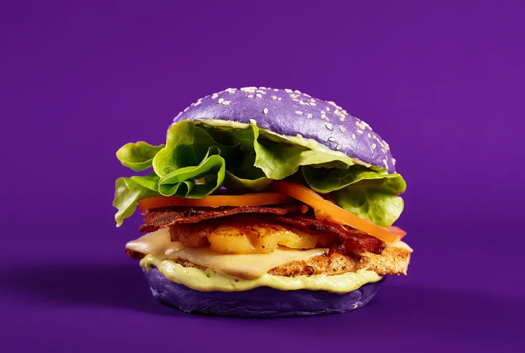YOMG California Dreaming Girleld Chicken Burger Menu Item - grilled chicken, swiss cheese, bacon, pineapple, lettuce, tomato, avocado mayo, purple bun
